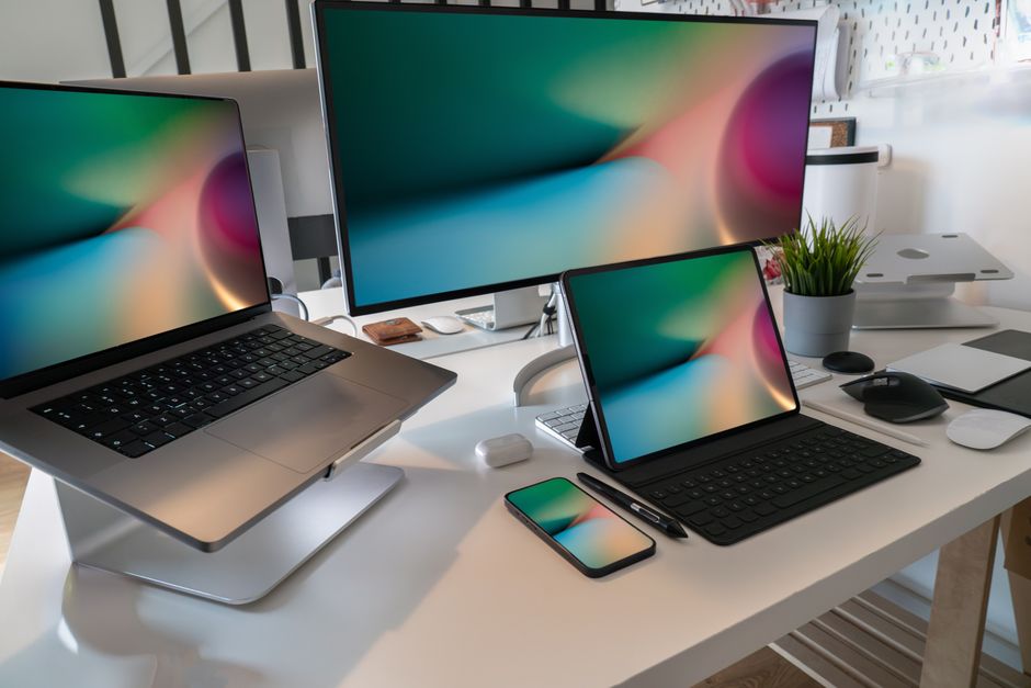 A contemporary workspace featuring a laptop, tablet, smartphone, and monitor