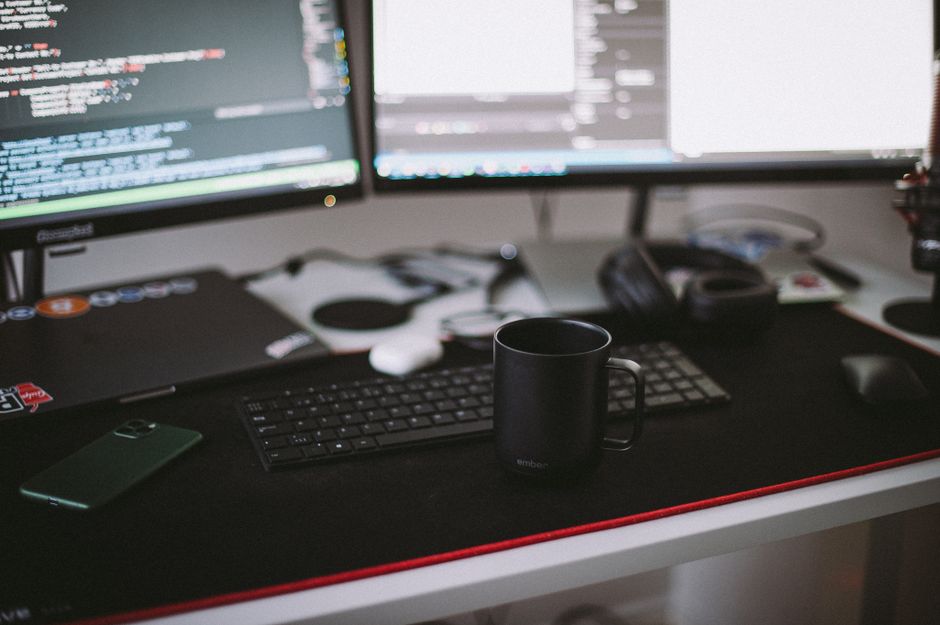 Cozy home office setup featuring dual monitors, a keyboard, and a black ceramic mug